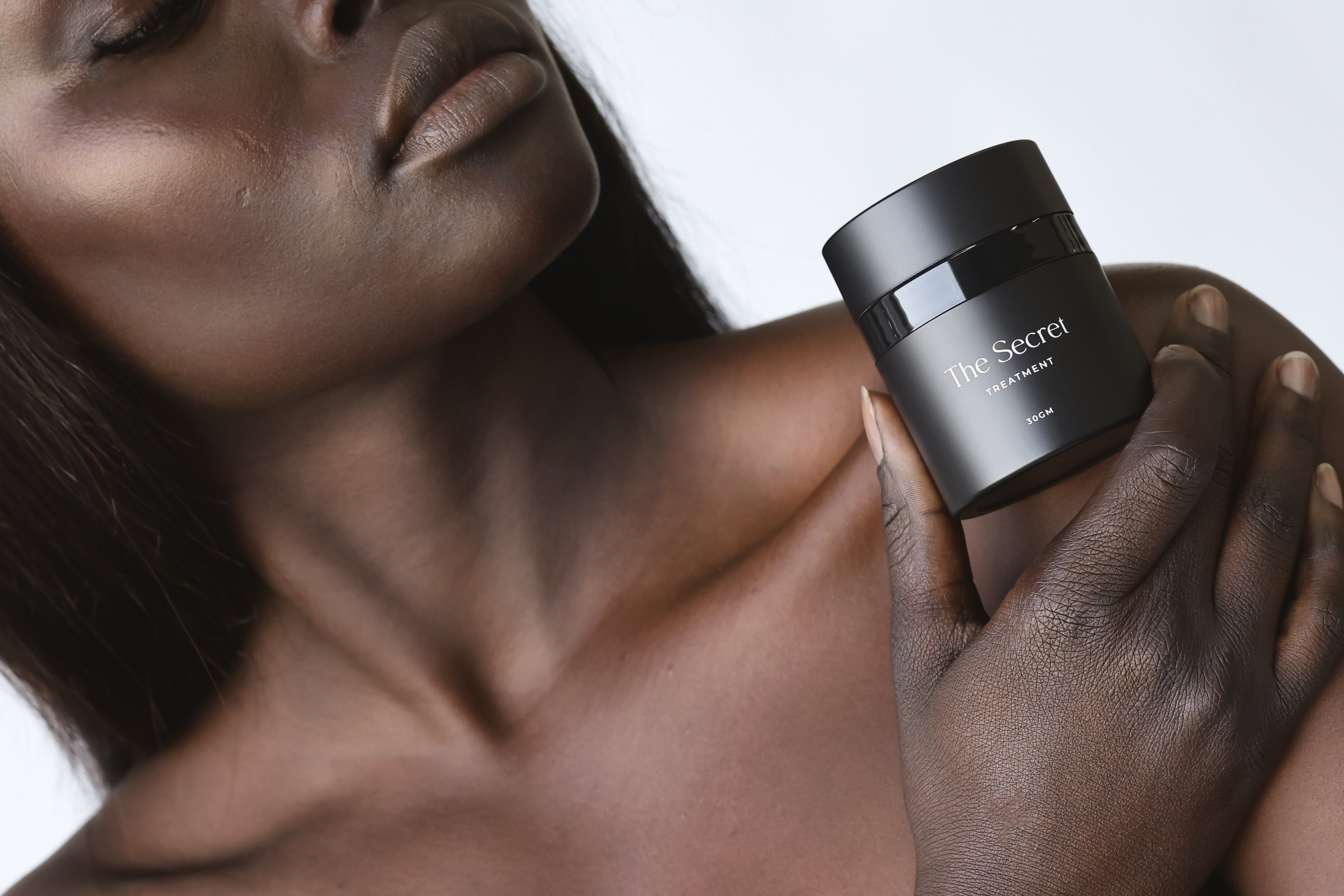 A model showcasing a spot treatment cream, highlighting its texture and packaging.