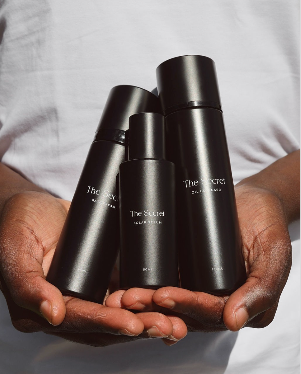 hands showcasing The Secret face oil and serum