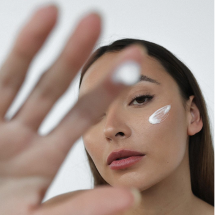 Woman posing for a photo during the application of facial cream while focusing on self-care for anxiety.