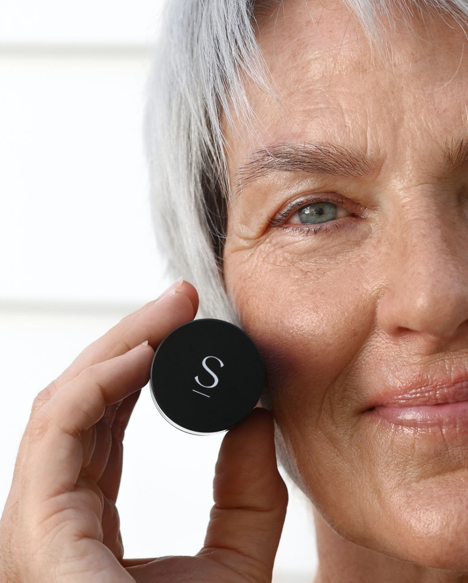 Woman holding skin care repair cream bottle